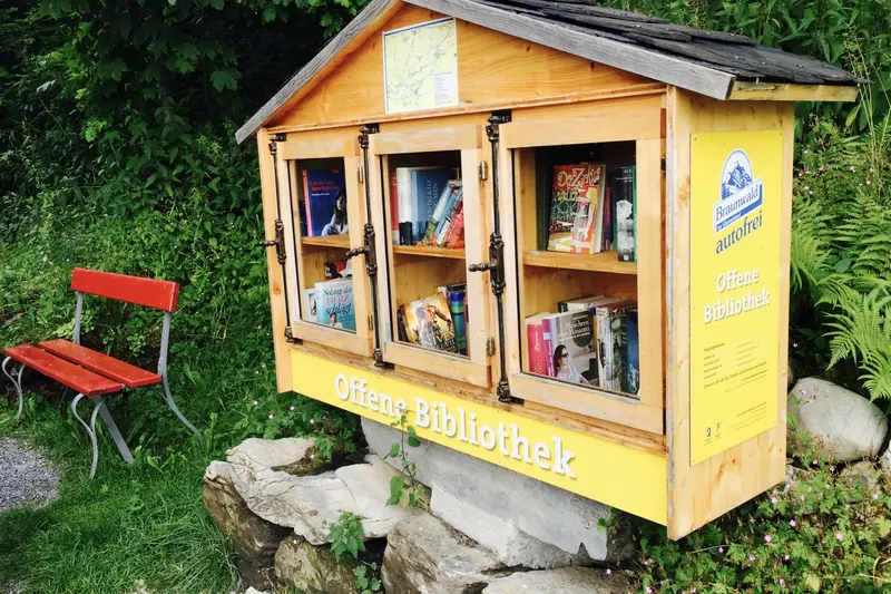 An open book cabinet and a red bench by the path