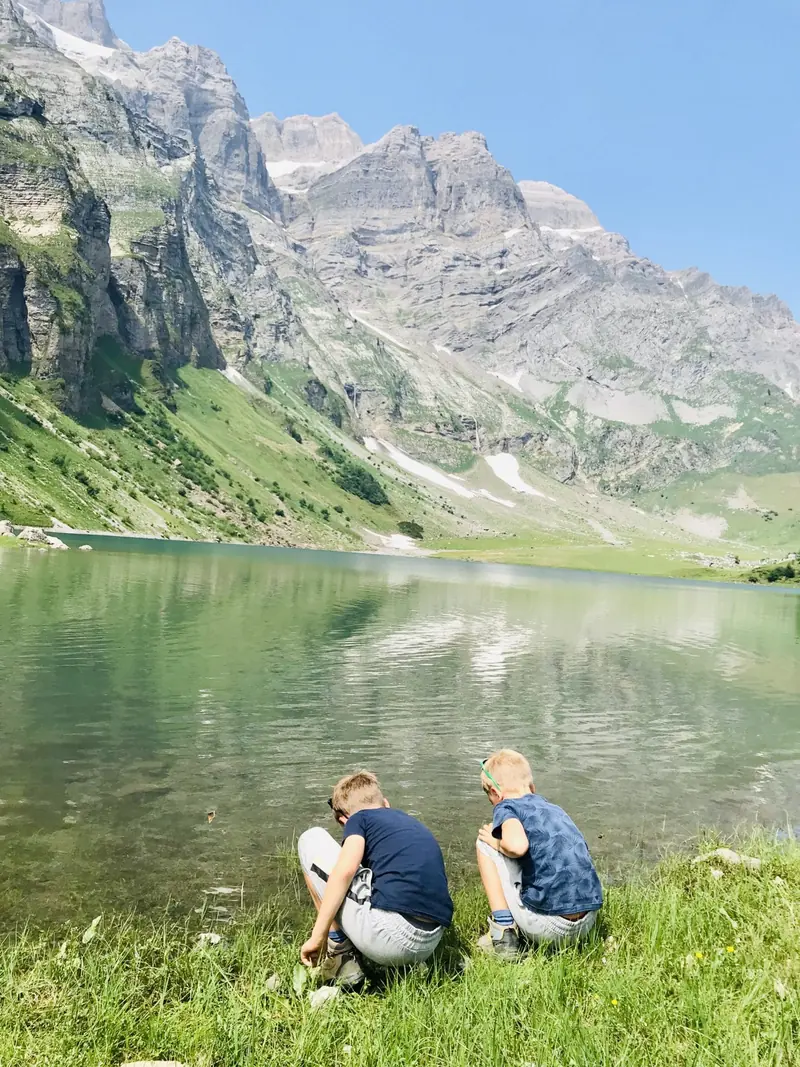 Two children on the shore of a mountain lake