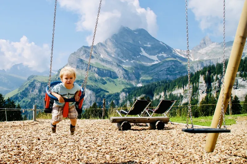 A toddler on a swing, a peak behind
