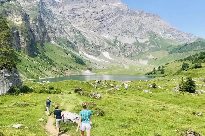 Walkers on a path down to a mountain lake